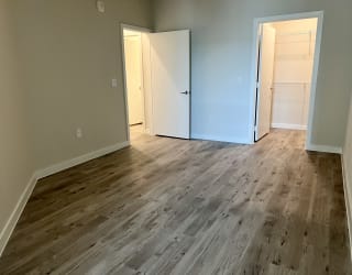 a bedroom with hardwood floors and grey walls