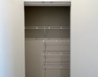 a walk in closet in a bedroom with white walls and a door that is open to a
