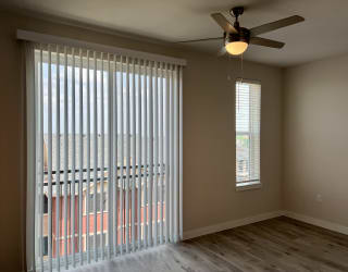 an empty bedroom with a ceiling fan and blinds