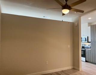 a living room with a ceiling fan and a kitchen in the background