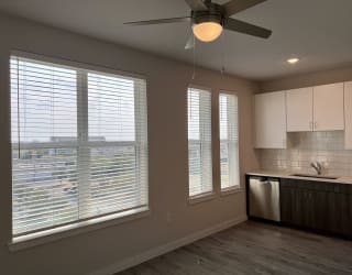 a kitchen with large windows and a ceiling fan