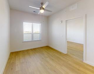 A room with a ceiling fan and a window with blinds.
