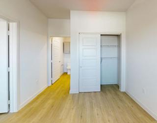 A room with white walls and wooden flooring with two white doors.