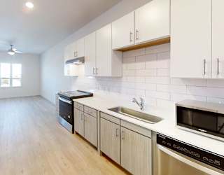 A kitchen with white cabinets and a wooden floor.
