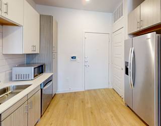 A kitchen with a refrigerator, sink, and microwave.