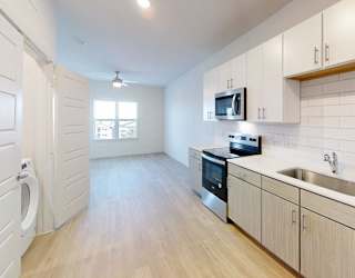 A kitchen with white cabinets and a wooden floor.