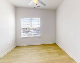 A room with a ceiling fan and a window with blinds.