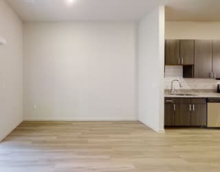 a bedroom with a sliding glass door and a kitchen in the background