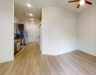 a bedroom with a ceiling fan and a kitchen in the background