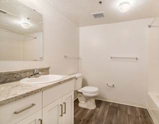 A bathroom with white cabinetry, a sink, toilet, and bathtub at Brentwood Park Apartments in LaVista, NE