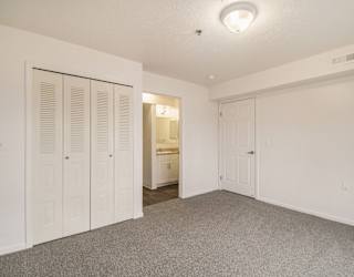 A bedroom with an ensuite and a door to a large closet at Brentwood Park Apartments in LaVista, NE
