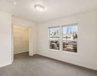 A bedroom with a carpeted floor, a walk in closet, and large windows at Brentwood Park Apartments in LaVista, NE