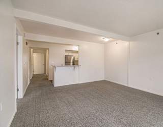 A large living and dining room with a carpeted floor at Brentwood Park Apartments in LaVista, NE