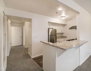 A kitchen with white cabinets, stainless steel appliances and a breakfast bar at Brentwood Park Apartments in LaVista, NE