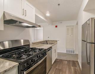 A kitchen with a gas stove and a refrigerator at Brentwood Park Apartments in LaVista, NE