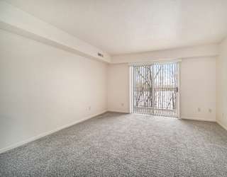 A living room with a carpeted floor and a slider to a balcony at Brentwood Park Apartments in LaVista, NE