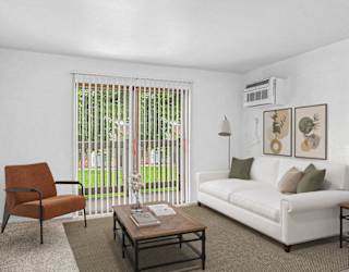 A living room with a white couch, a brown chair, and a coffee table at Concord Place Apartments in Kalamazoo, Michigan 49009