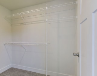 Walk in closet with wardrobe organizers at Copper Creek Apartment Homes, Maize