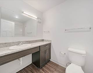 A white toilet sits next to a sink in a bathroom at Copper Creek Apartment Homes, Kansas, 67101