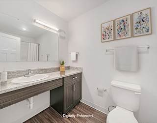 A bathroom with a toilet, sink, mirror, and pictures on the wall at Copper Creek Apartment Homes, Kansas, 67101
