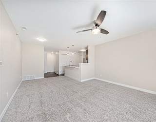 A spacious living room with a ceiling fan and carpeted floor at Copper Creek Apartment Homes, Kansas, 67101