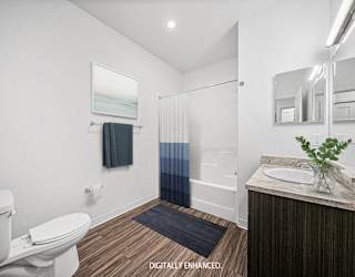 A master bathroom with a toilet, sink, and mirror at Copper Creek Apartment Homes, Maize, Kansas