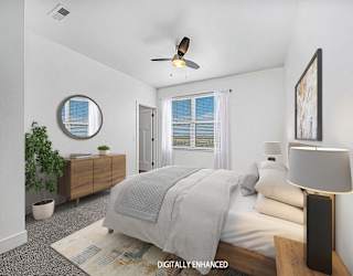 A bedroom with a bed, a ceiling fan, and a window with blinds at Copper Creek Apartment Homes, Maize, Kansas