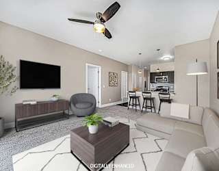 A living room with a grey armchair, a white sofa, a wooden coffee table at Copper Creek Apartment Homes, Maize, Kansas