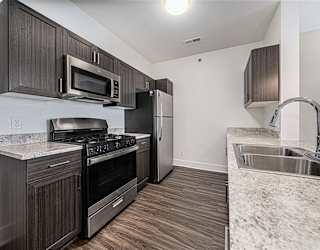 A kitchen with dark wood cabinets and stainless steel appliances at Copper Creek Apartment Homes, Maize