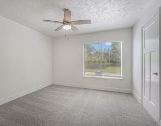 large bedroom with a ceiling fan and a window at The Crossings Apartments, Michigan, 49508