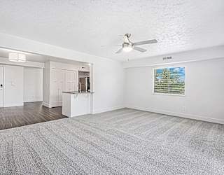 A living room with a ceiling fan and carpeted floor at The Crossings Apartments in Grand Rapids, MI