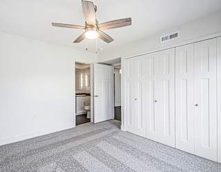 A bedroom with a ceiling fan and a carpeted floor at The Crossings Apartments in Grand Rapids, MI