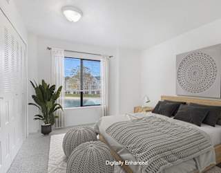 A bedroom with a large bed and a large window with a view at Dupont Lakes Apartments in Fort Wayne, IN