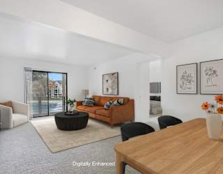 A living room with a brown sofa and a wooden table at Dupont Lakes Apartments in Fort Wayne, IN