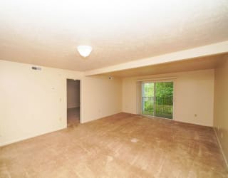A living room with a slider to a balcony at Dupont Lakes Apartments, Fort Wayne
