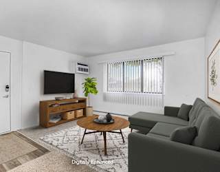 A garden style living room with a large window at Fairlane Apartments in MI 49037
