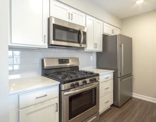 a kitchen with white cabinets and stainless steel appliances at Hillside Apartments, Wixom