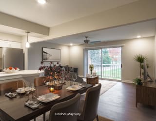 a dining area with a table and chairs and a kitchen in the background at Hillside Apartments, Wixom, Michigan