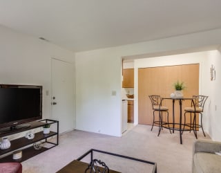 a living room with a flat screen tv and a dining room table in the background  at Sycamore Creek Apartments, Lake Orion