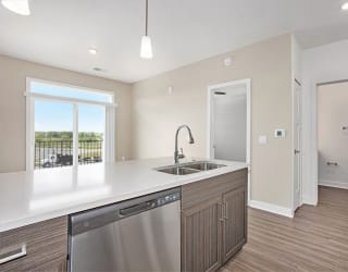 a kitchen with a sink and a door to a hallway at Meadowbrooke Apartment Homes, Grand Rapids