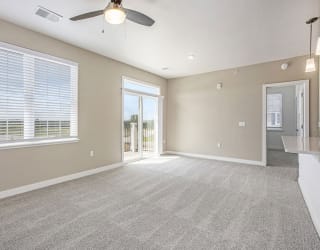 an empty living room with a ceiling fan and a window at Meadowbrooke Apartment Homes, Grand Rapids, MI