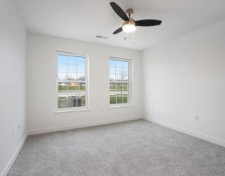 an empty living room with a ceiling fan and two windows at Meadowbrooke Apartment Homes, Grand Rapids, Michigan