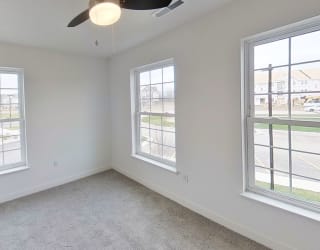 an empty room with three windows and a ceiling fan at Meadowbrooke Apartment Homes, Grand Rapids, Michigan