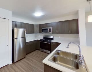a kitchen with a stainless steel refrigerator and a sink at Meadowbrooke Apartment Homes, Grand Rapids