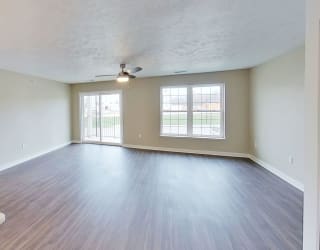 an empty living room with a ceiling fan and a window at Meadowbrooke Apartment Homes, Michigan