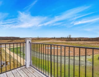 a view of a field from a balcony with a blue sky at Meadowbrooke Apartment Homes, Grand Rapids