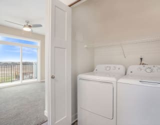 a white laundry room with two washes and a dryer at Meadowbrooke Apartment Homes, Grand Rapids