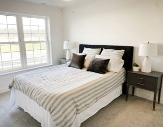a bedroom with a bed and two nightstands and a window at Meadowbrooke Apartment Homes, Michigan, 49512