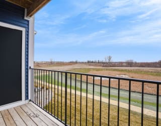 the view from the deck of a home with a gate and a field at Meadowbrooke Apartment Homes, Grand Rapids