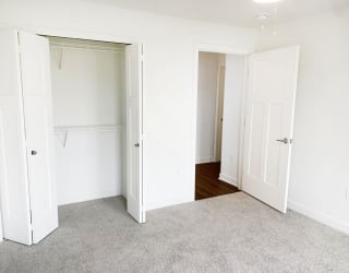 an empty bedroom with white closet doors and a carpet at Meadowbrooke Apartment Homes, Grand Rapids